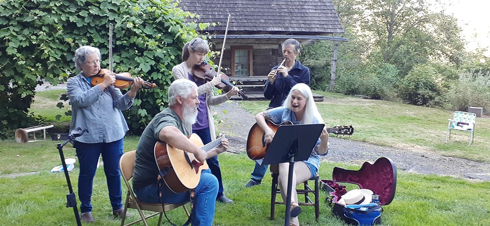 Fiddlers and guitarists outside the Baker Cabin